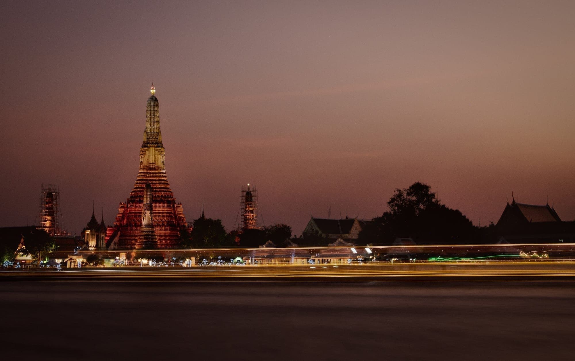 Wat Arun lit up above the river in Bangkok at dusk