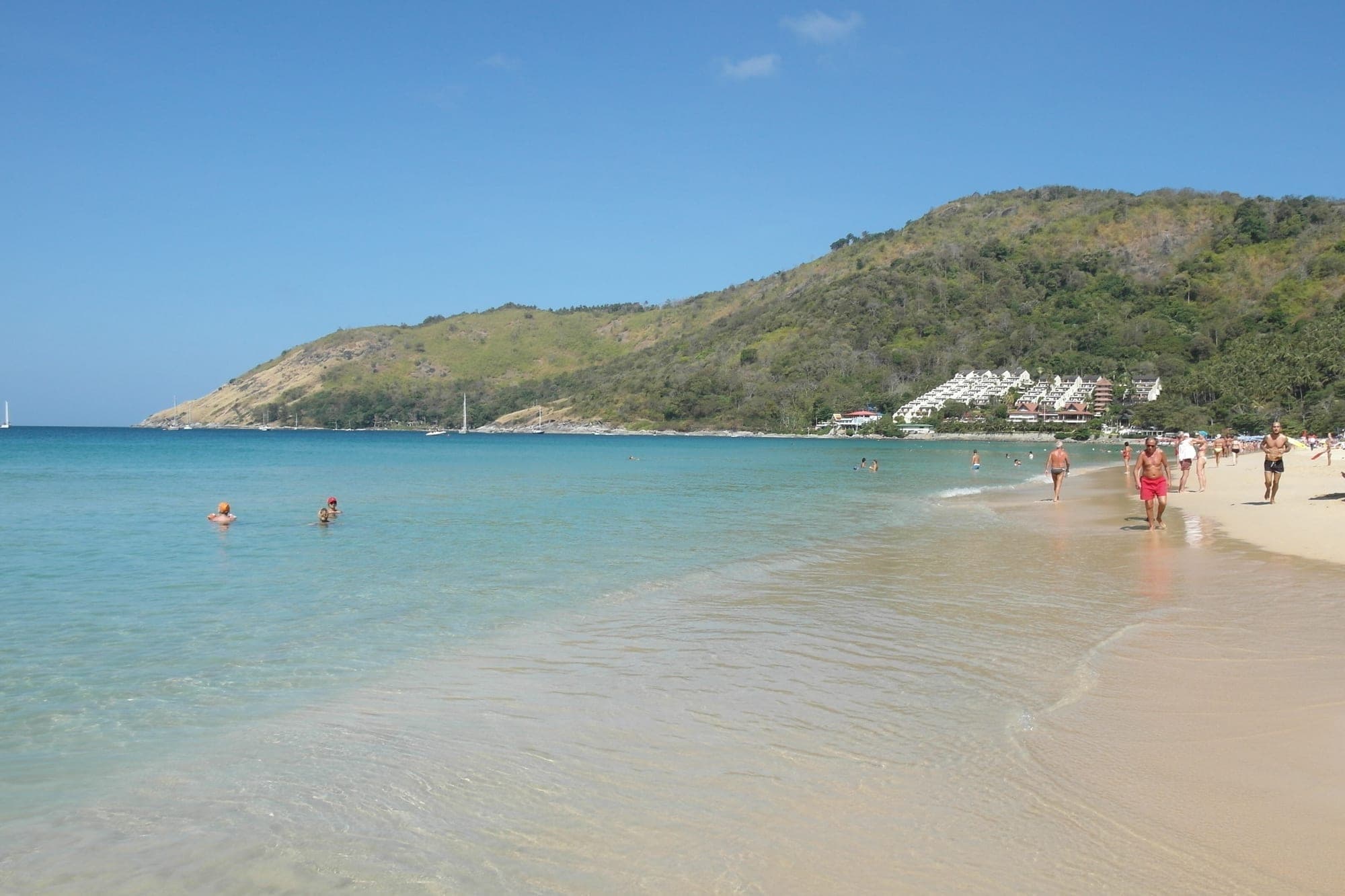 A calm shallow beach with families in the water