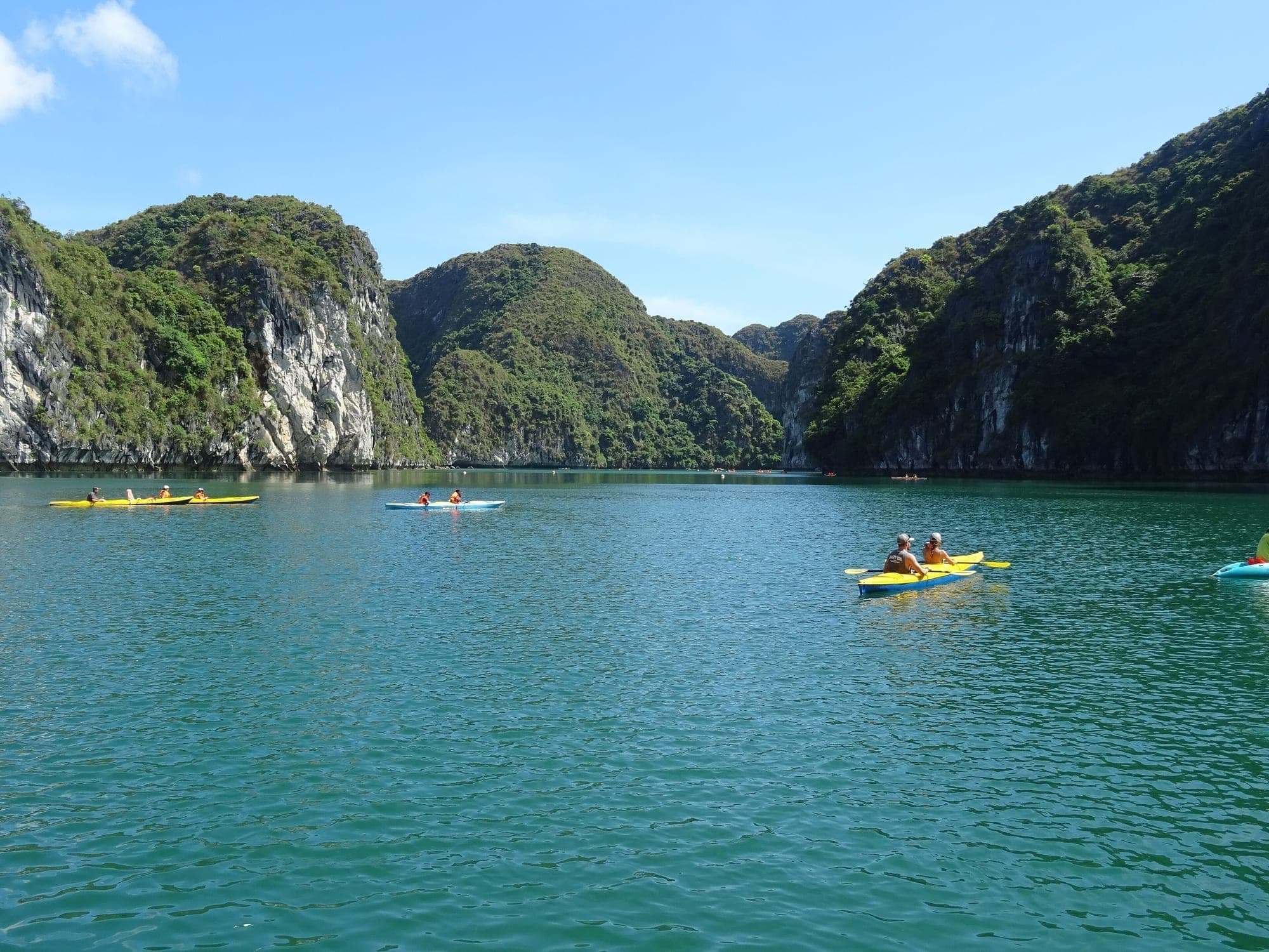 Kayakers paddling between limestone cliffs in Ha Long Bay