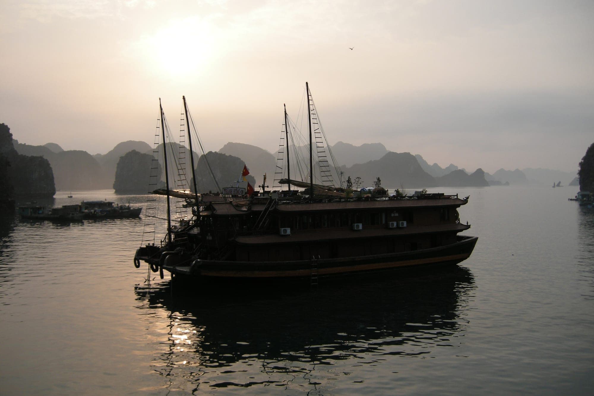 A traditional junk boat at sunset in Ha Long Bay